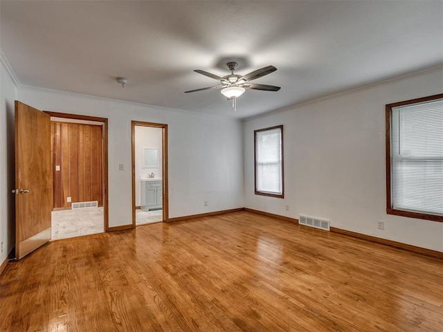 unfurnished bedroom featuring baseboards, visible vents, ornamental molding, and light wood-style floors