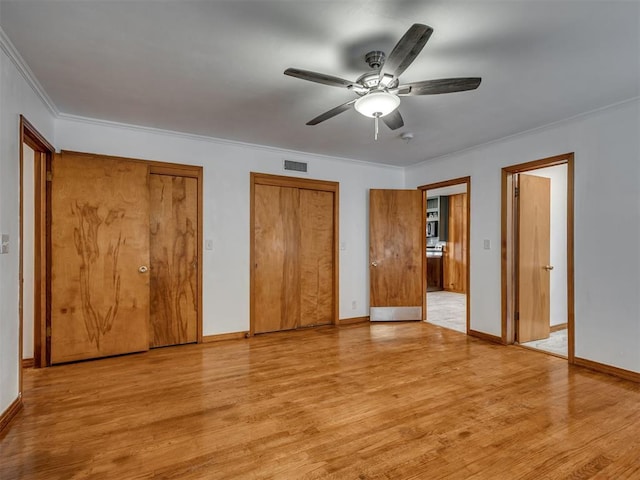 unfurnished bedroom with visible vents, ornamental molding, multiple closets, light wood-style floors, and baseboards