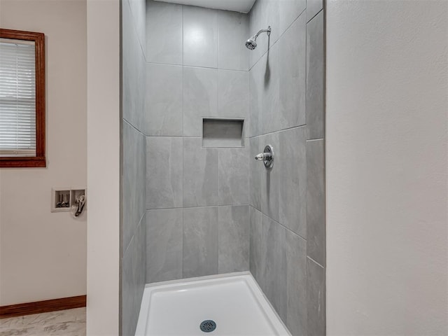 bathroom with baseboards, marble finish floor, and tiled shower