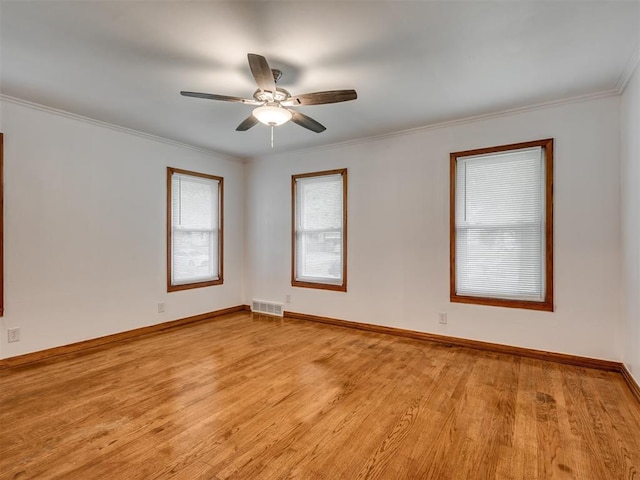 unfurnished room with a ceiling fan, visible vents, light wood-type flooring, baseboards, and ornamental molding