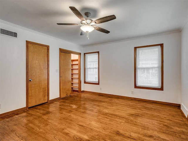 unfurnished bedroom with baseboards, two closets, light wood-style flooring, and visible vents