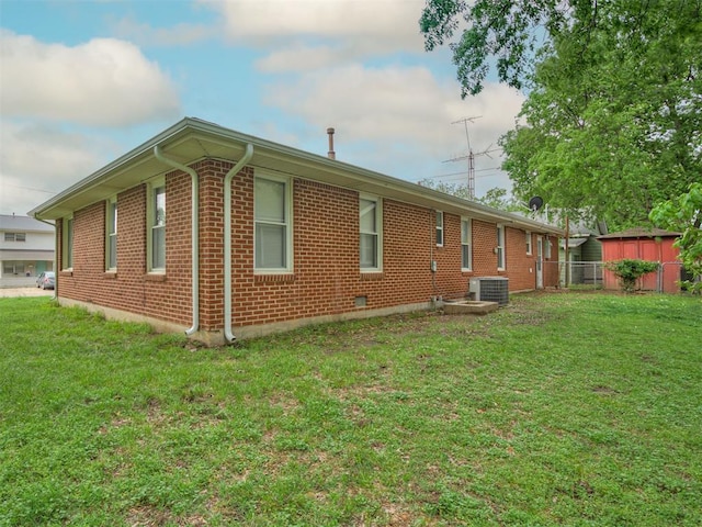 view of side of home featuring a lawn, central AC unit, fence, and brick siding