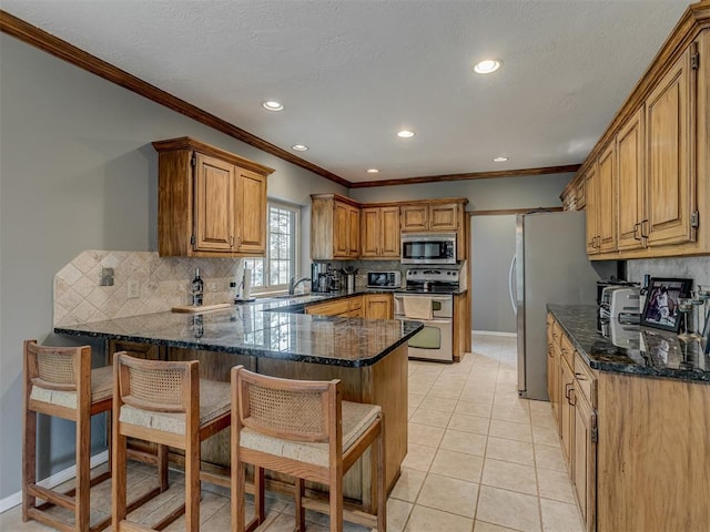 kitchen featuring decorative backsplash, ornamental molding, a peninsula, a breakfast bar, and appliances with stainless steel finishes