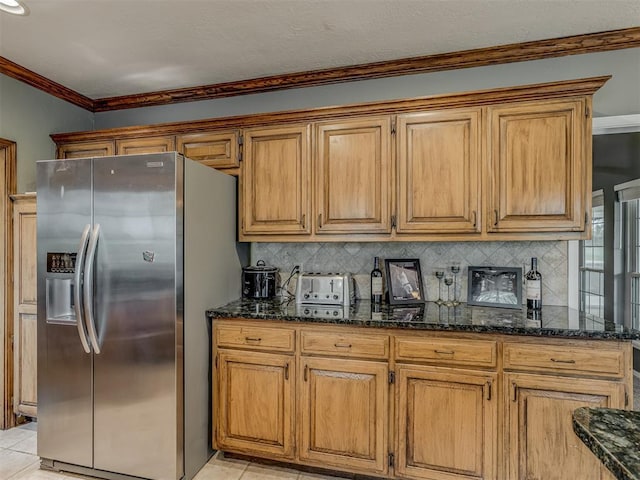 kitchen with backsplash, light tile patterned flooring, stainless steel fridge, and dark stone countertops
