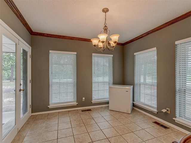 unfurnished dining area with visible vents, baseboards, an inviting chandelier, ornamental molding, and light tile patterned flooring