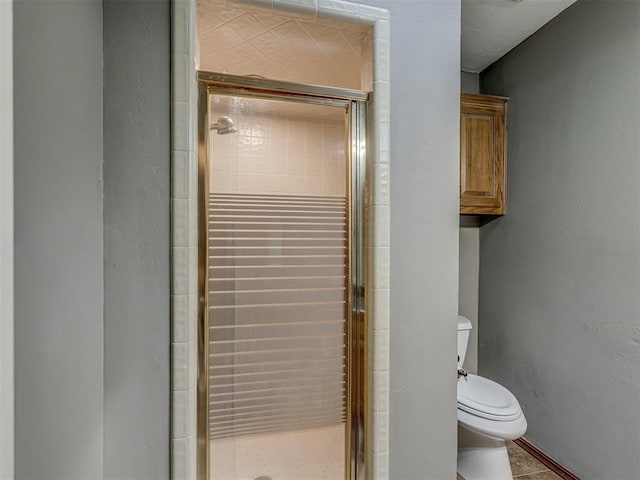 bathroom with a textured wall, a stall shower, and toilet