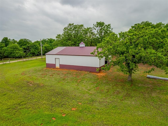 view of yard featuring a pole building, fence, and an outbuilding