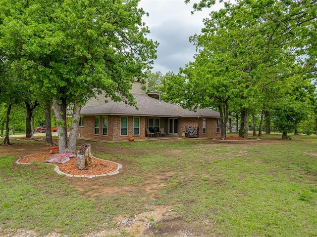 view of front of house with brick siding, a front yard, and roof with shingles