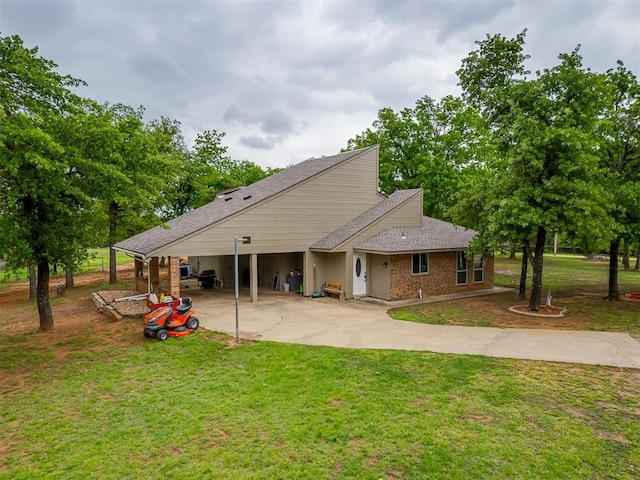 rear view of house featuring driveway, roof with shingles, brick siding, a yard, and a carport