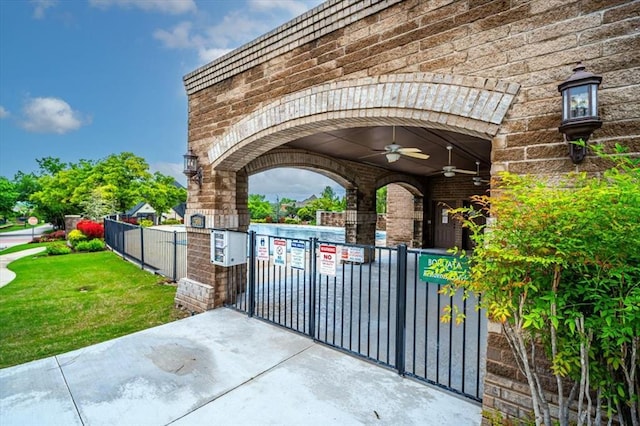 view of gate featuring fence and a ceiling fan