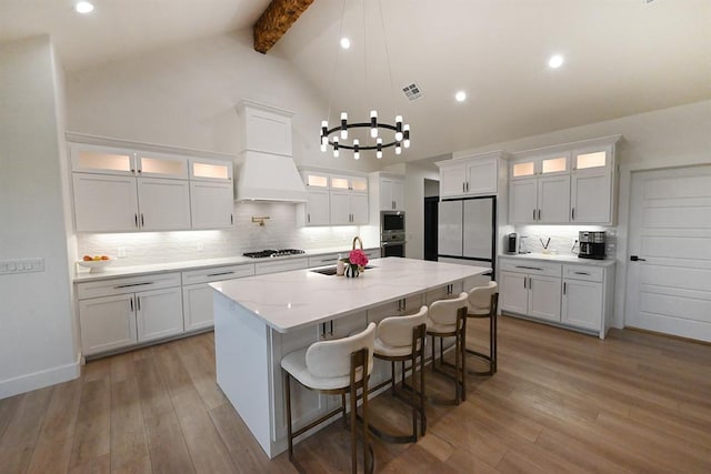 kitchen with wood finished floors, white cabinetry, tasteful backsplash, a sink, and stainless steel appliances