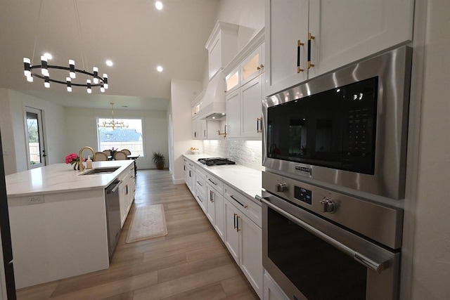 kitchen with white cabinets, an inviting chandelier, a sink, a kitchen island with sink, and stainless steel appliances