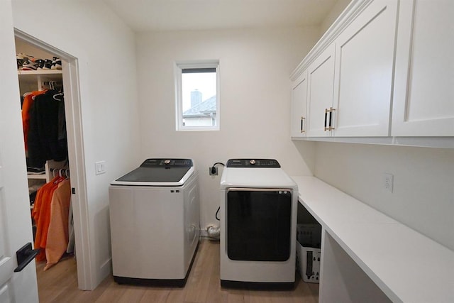 washroom featuring separate washer and dryer, cabinet space, and light wood-type flooring