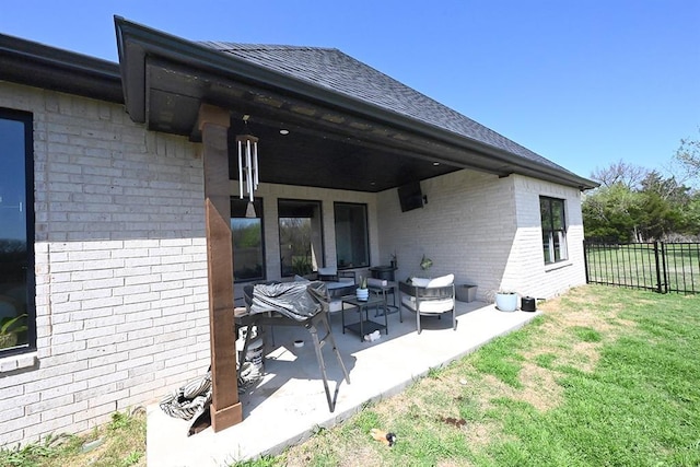 rear view of house featuring fence, a patio, brick siding, an outdoor living space, and a yard