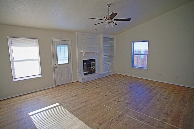 unfurnished living room with ceiling fan, a fireplace, baseboards, wood finished floors, and vaulted ceiling