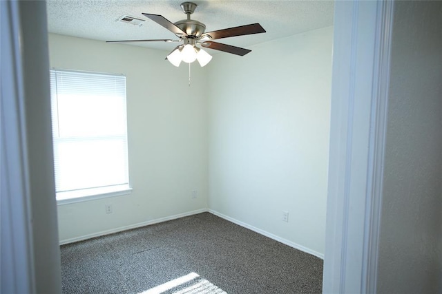 carpeted empty room featuring visible vents, a ceiling fan, baseboards, and a wealth of natural light