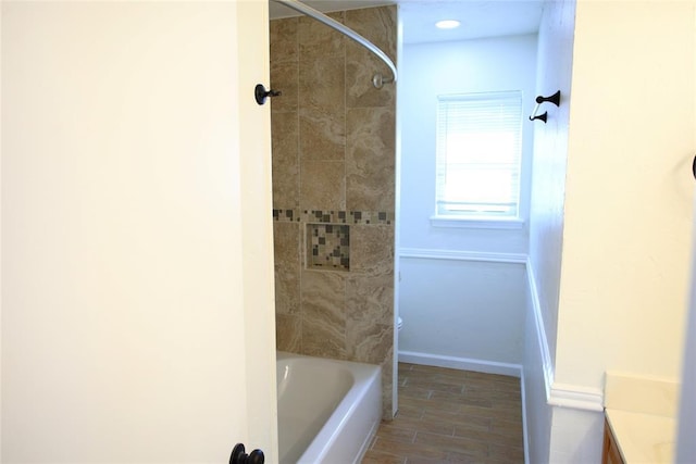 bathroom featuring vanity, baseboards, bathing tub / shower combination, and wood finished floors