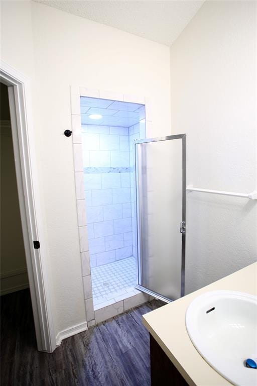 full bathroom featuring wood finished floors, a stall shower, and vanity