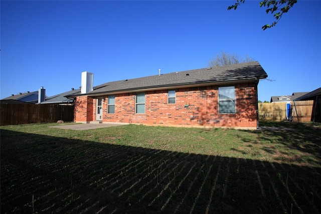 rear view of house with a fenced backyard, a yard, a patio area, and brick siding