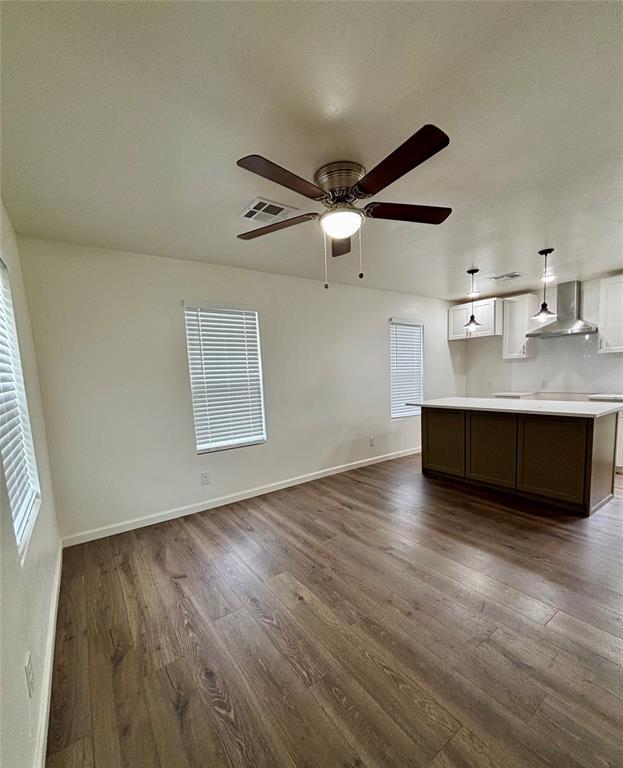 unfurnished living room featuring visible vents, dark wood-style flooring, ceiling fan, and baseboards