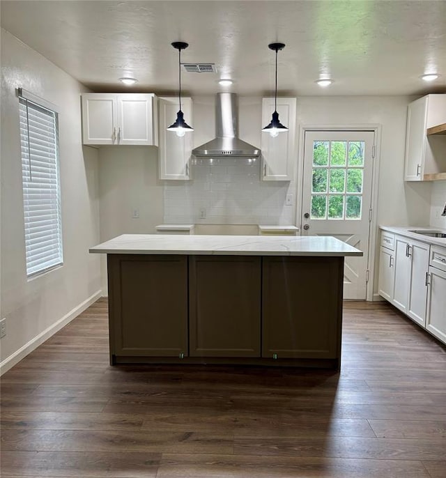 kitchen with white cabinetry, dark wood finished floors, a sink, and wall chimney exhaust hood
