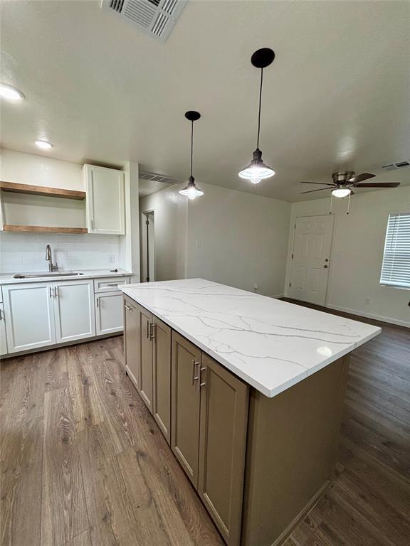 kitchen with a sink, open shelves, dark wood finished floors, and visible vents