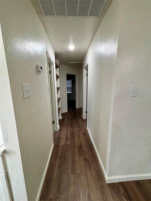 corridor featuring baseboards, wood finished floors, and visible vents