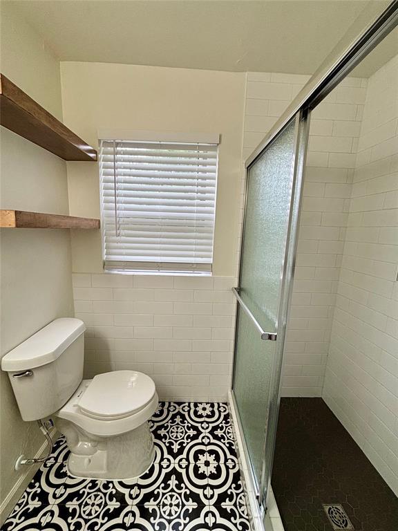 full bathroom featuring toilet, a shower stall, and tile patterned flooring