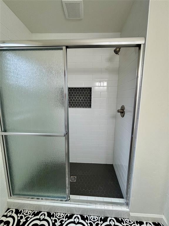 bathroom with a shower stall and visible vents