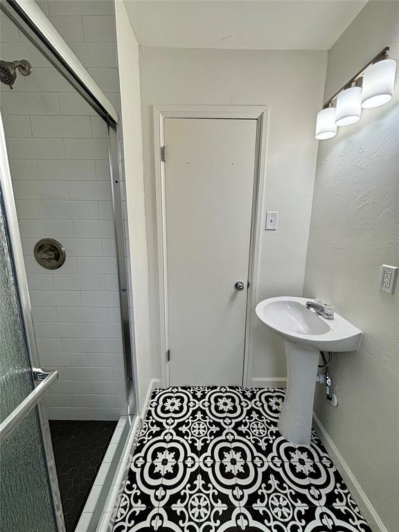 full bathroom featuring baseboards, a sink, tile patterned floors, and a stall shower