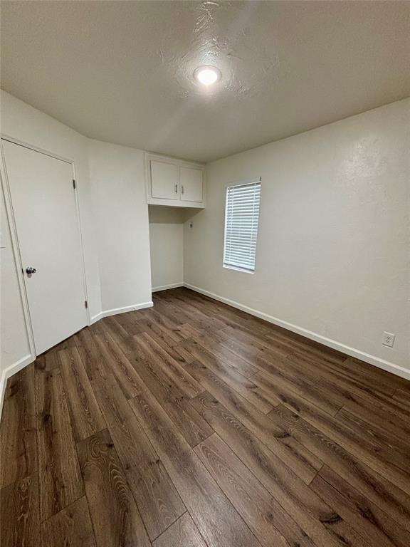 interior space featuring baseboards and dark wood-type flooring