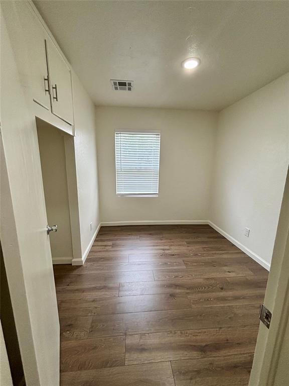 empty room featuring baseboards, dark wood-type flooring, recessed lighting, and visible vents