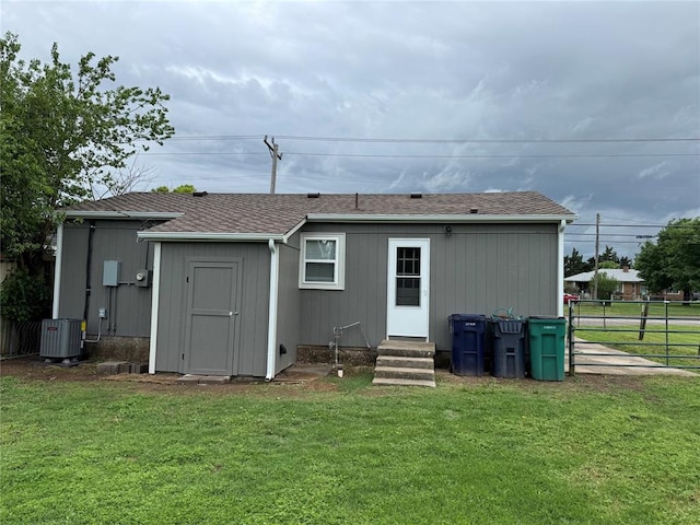 rear view of house with central AC unit, fence, a yard, and entry steps