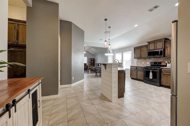 kitchen featuring visible vents, stainless steel microwave, tasteful backsplash, gas stove, and decorative light fixtures