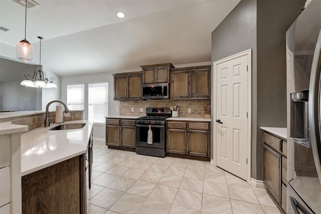 kitchen with hanging light fixtures, appliances with stainless steel finishes, decorative backsplash, and a sink