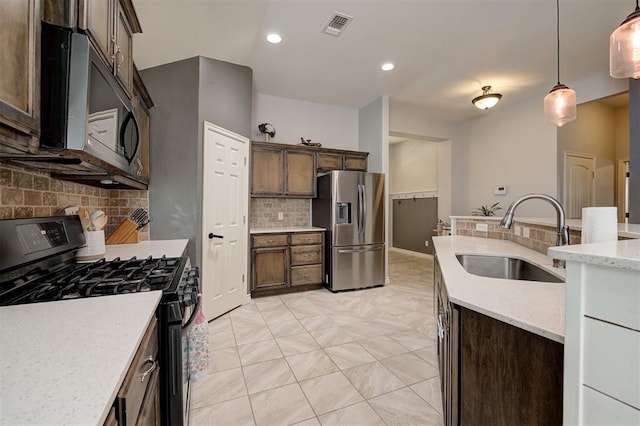 kitchen featuring a sink, gas stove, decorative light fixtures, backsplash, and stainless steel refrigerator with ice dispenser