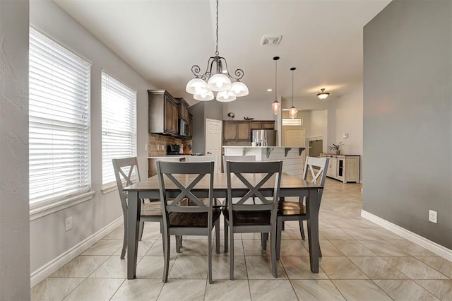 dining space with light tile patterned flooring, baseboards, a chandelier, and visible vents