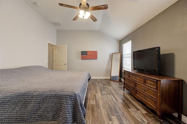 bedroom featuring visible vents, lofted ceiling, wood finished floors, baseboards, and a ceiling fan