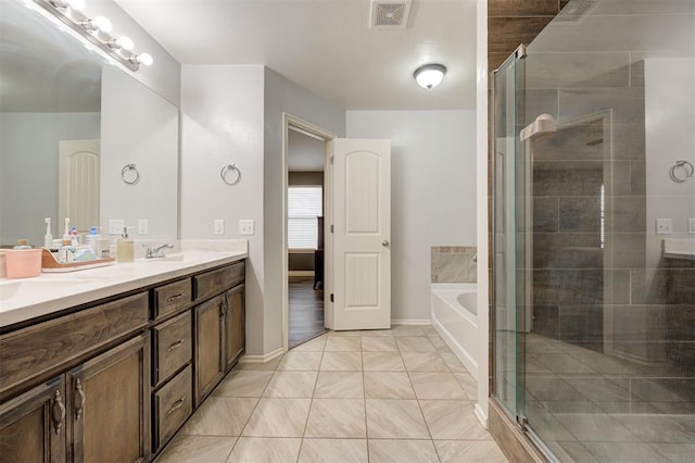 full bathroom with double vanity, a garden tub, visible vents, a shower stall, and a sink