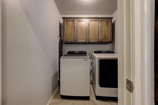 laundry area with baseboards, cabinet space, and washing machine and clothes dryer