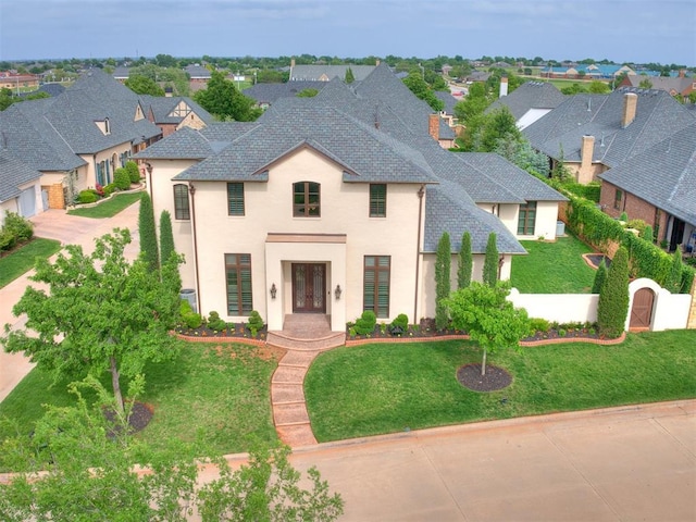 french country home featuring fence, a residential view, a shingled roof, a front yard, and french doors
