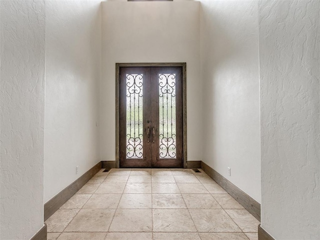 foyer entrance with baseboards, a textured wall, and french doors