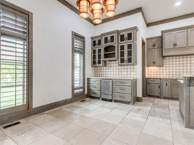 kitchen with a healthy amount of sunlight, decorative backsplash, an inviting chandelier, and visible vents