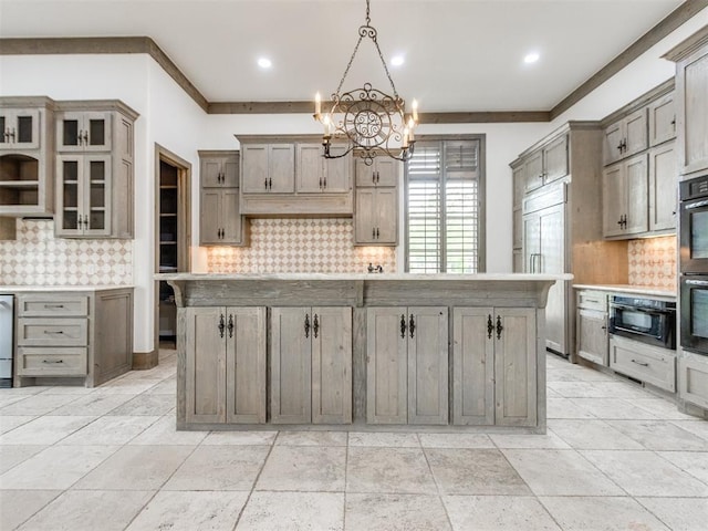 kitchen featuring a center island, decorative backsplash, paneled fridge, and a notable chandelier