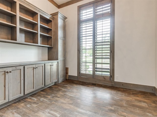 unfurnished office featuring baseboards, a healthy amount of sunlight, and wood finished floors
