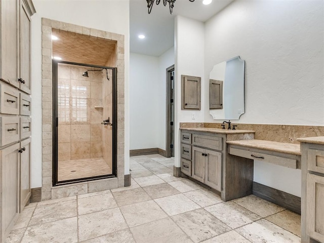 full bath with vanity, baseboards, a shower stall, and stone tile floors