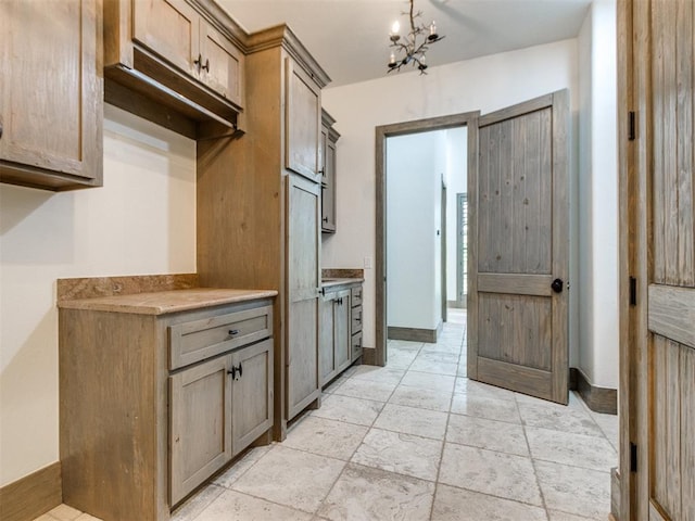 kitchen featuring light countertops, baseboards, and a chandelier