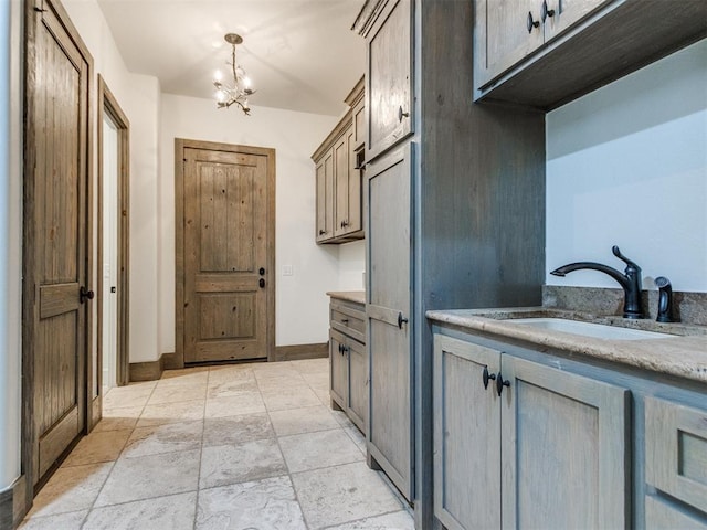 interior space featuring stone finish floor, baseboards, an inviting chandelier, and a sink
