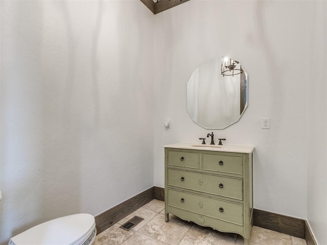 half bathroom with visible vents, baseboards, toilet, and vanity