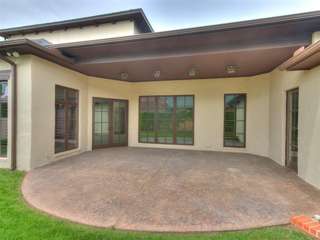 rear view of property featuring french doors, a patio area, and stucco siding
